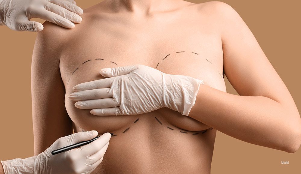 a surgeon's gloved hands trace a woman's breasts to help determine her ideal implant size